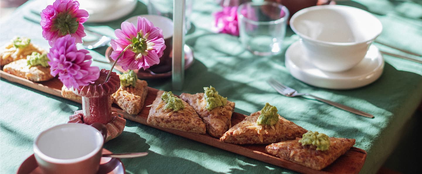 Mesa vestida con finger food, flores y vajilla blanca