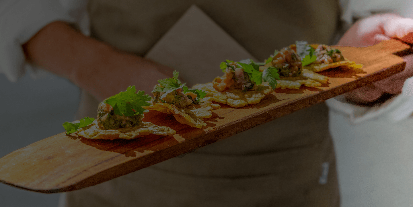 Mesero de Jacinto sirviendo tostadas de ceviche sobre una tabla de madera