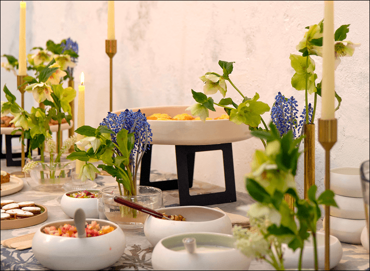 Mesa de evento corporativo con bowls de porcelana, flores y velas