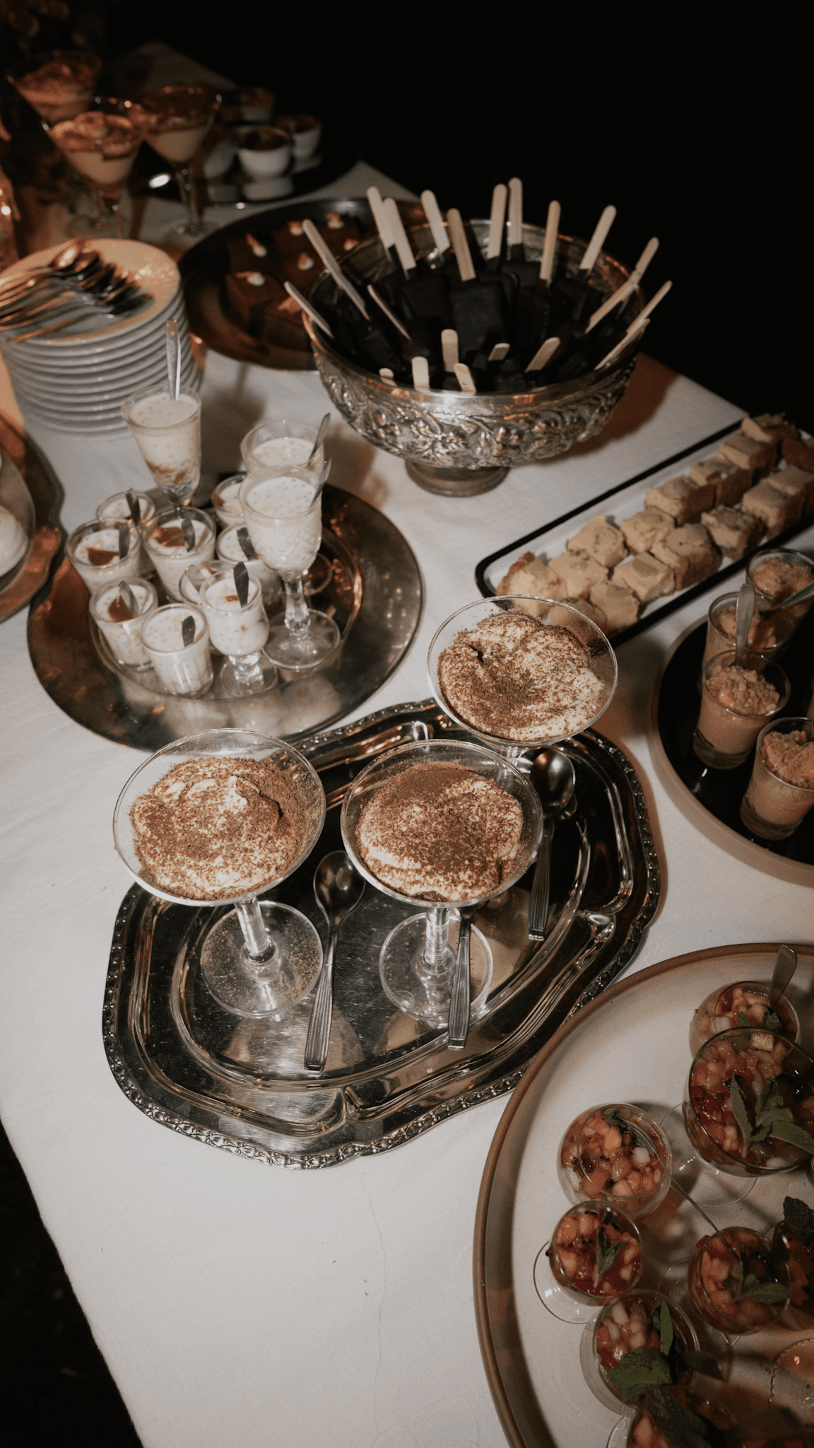 Mesa dulce con postres servidos en copas y bandejas